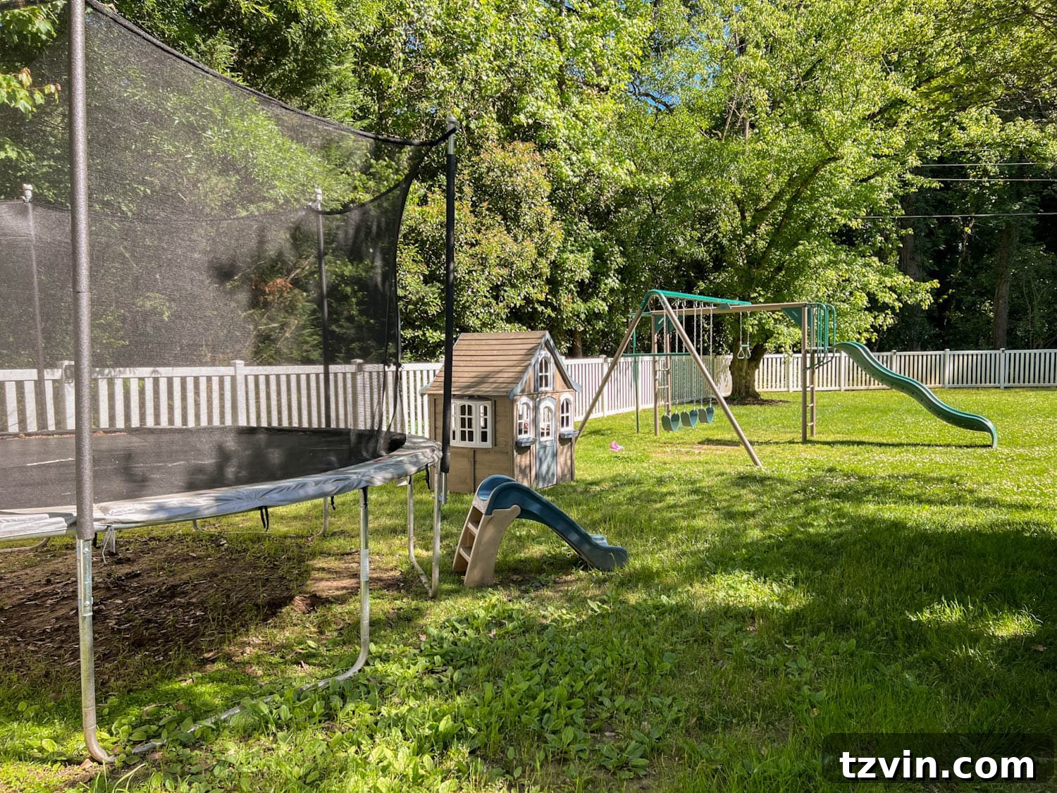 Untidy side yard play area before its transformation, showing a worn trampoline and bare ground.