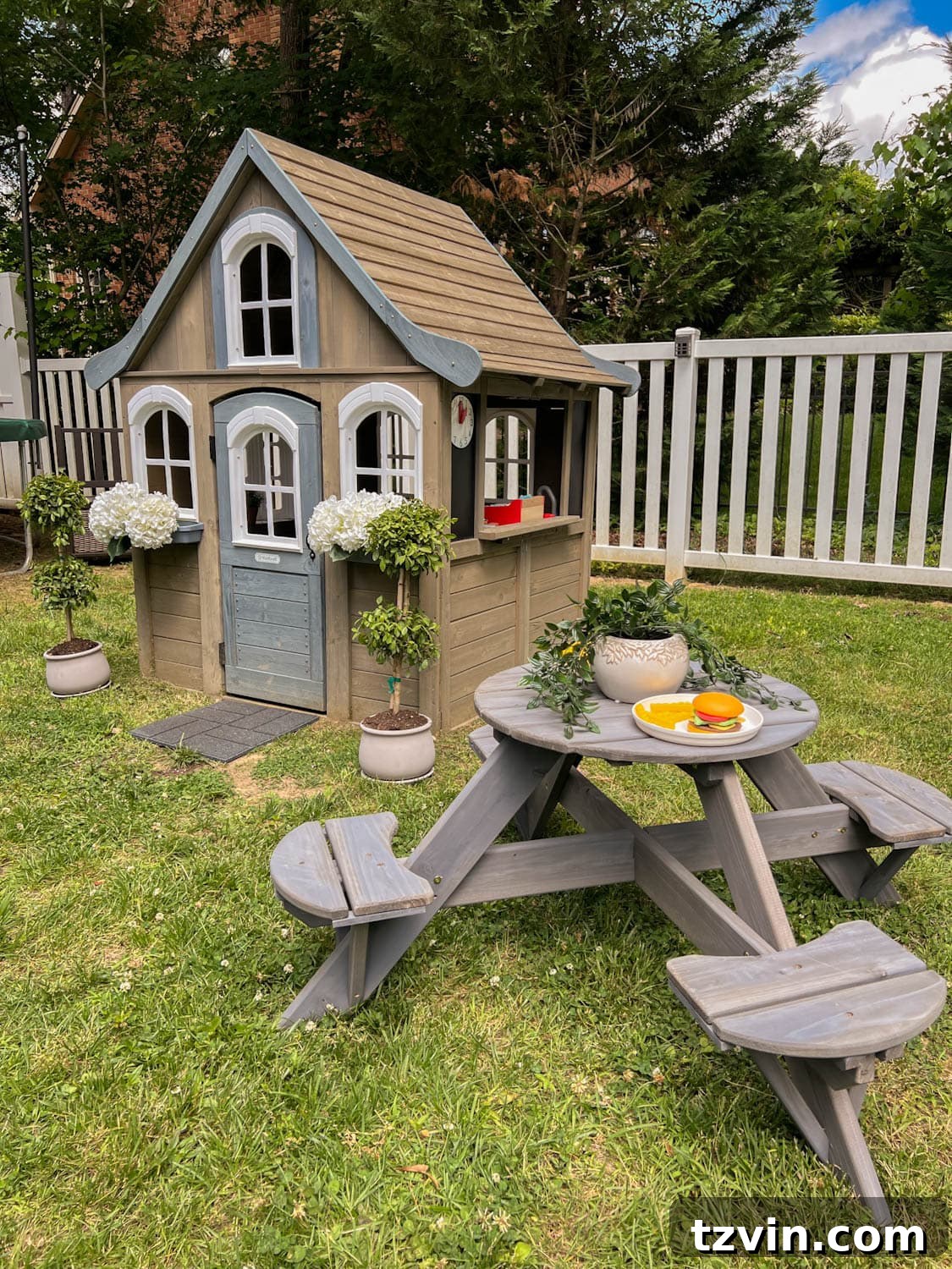 Charming kids outdoor picnic table situated next to a delightful playhouse in a sunny side yard play area.