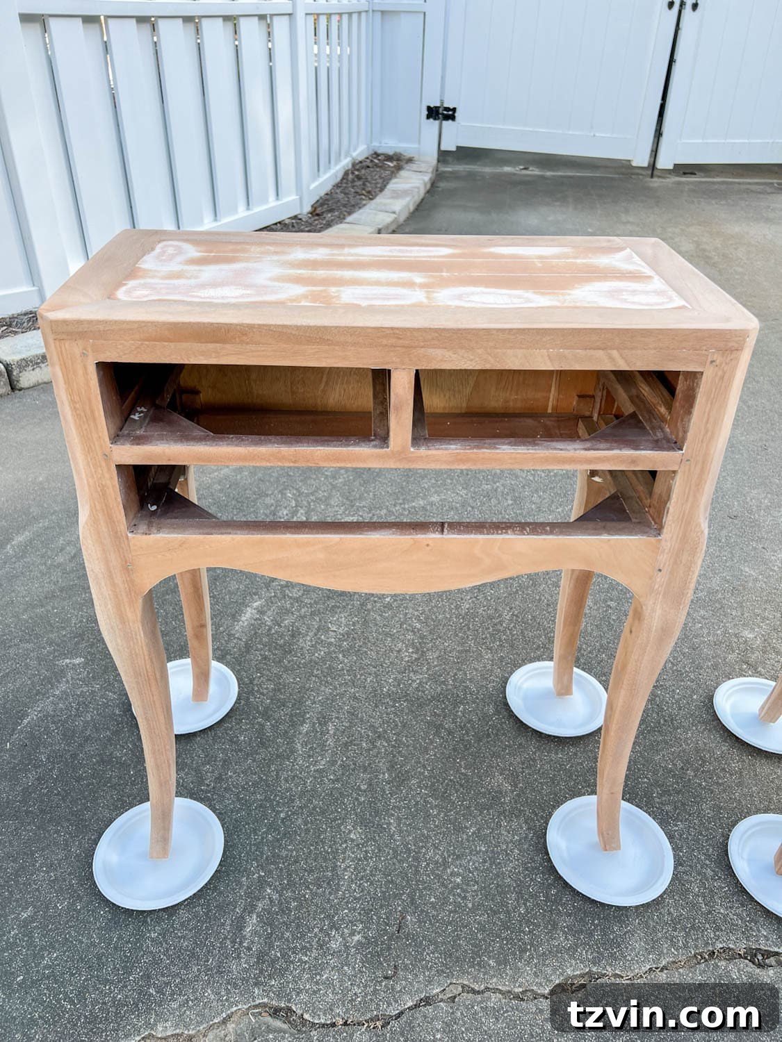 A perfectly sanded bedside table, with all distressed paint removed, showcasing a smooth, raw wood surface ready for priming and a gloss paint application.