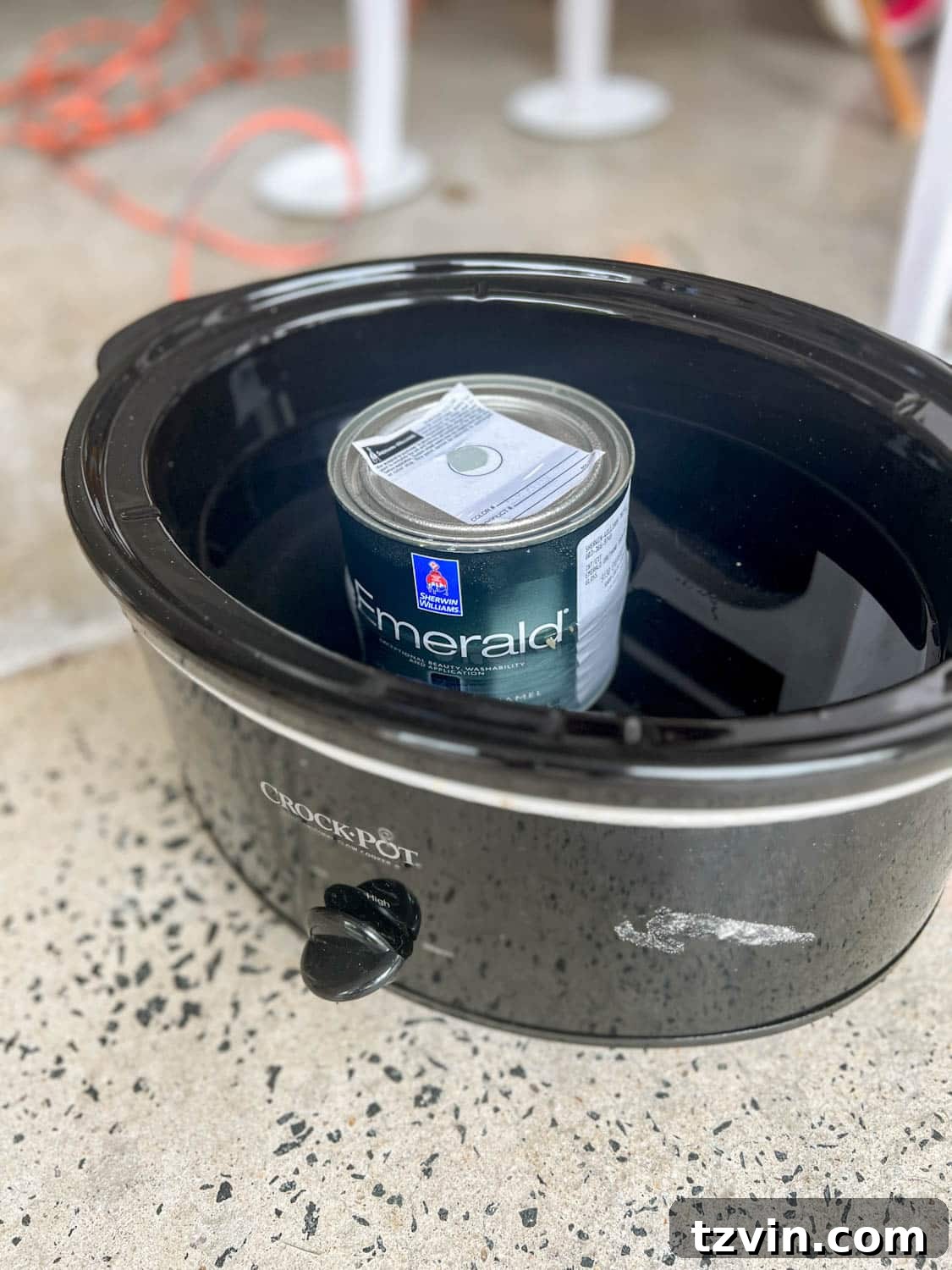 A can of gloss paint warming gently in a slow cooker filled with water, a clever DIY trick for achieving a perfectly smooth, brushstroke-free paint finish.