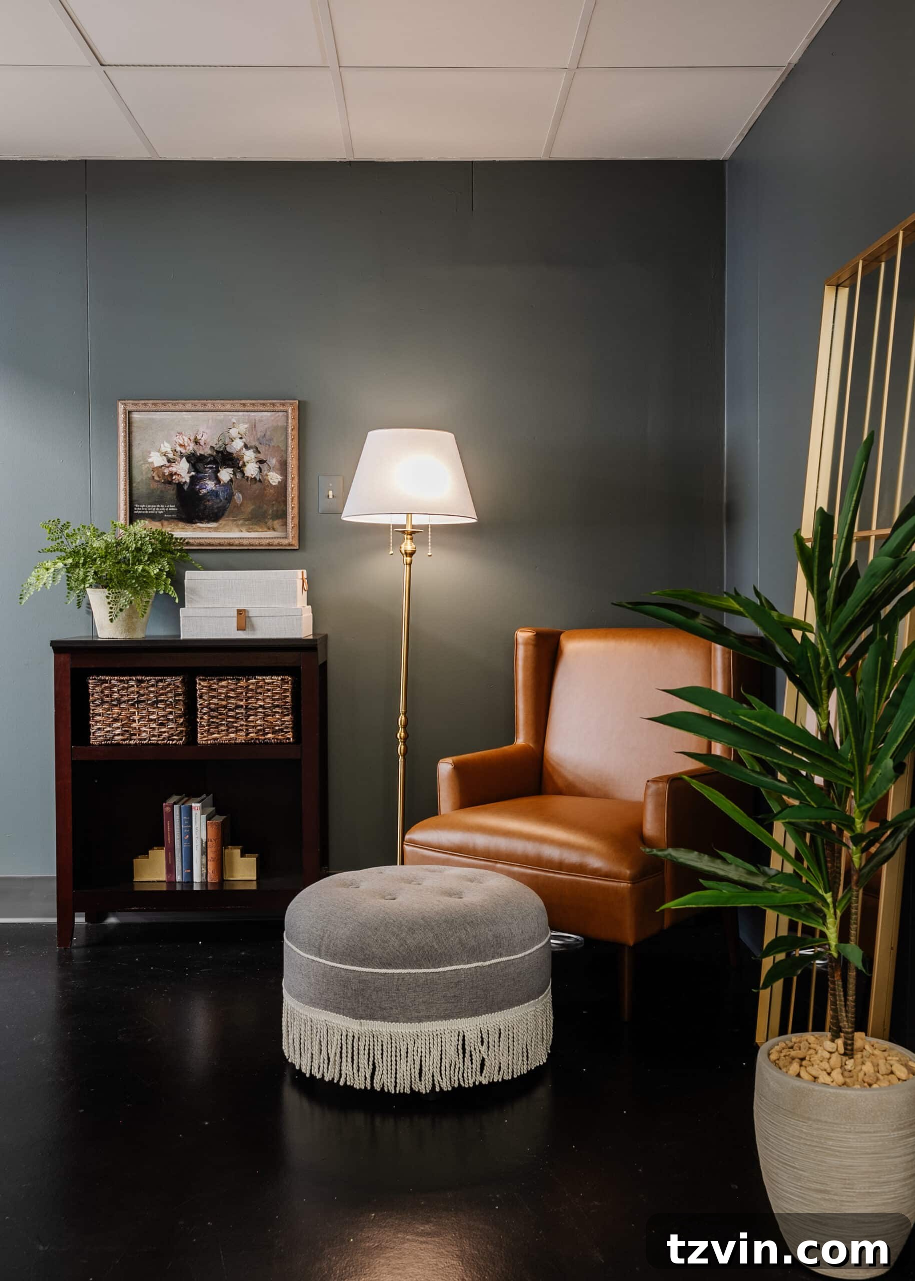Warm Up Your Workday Cozy Conference Room Ideas for an Office Refresh 4 Cozy reading corner in a transformed office with a leather armchair and a gray fringe footstool, bathed in soft lighting.