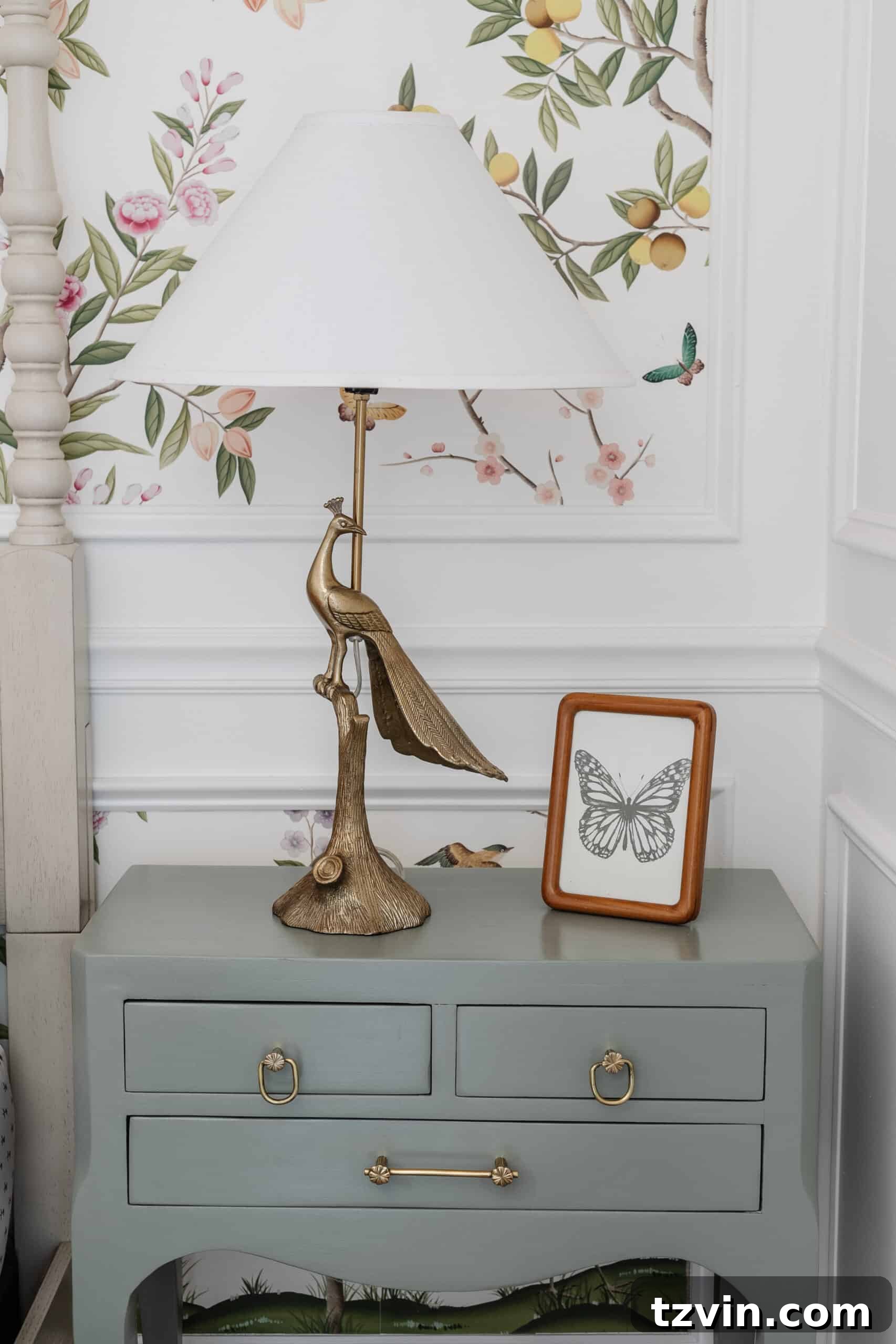 gold peacock lamp on a sage green bedside table