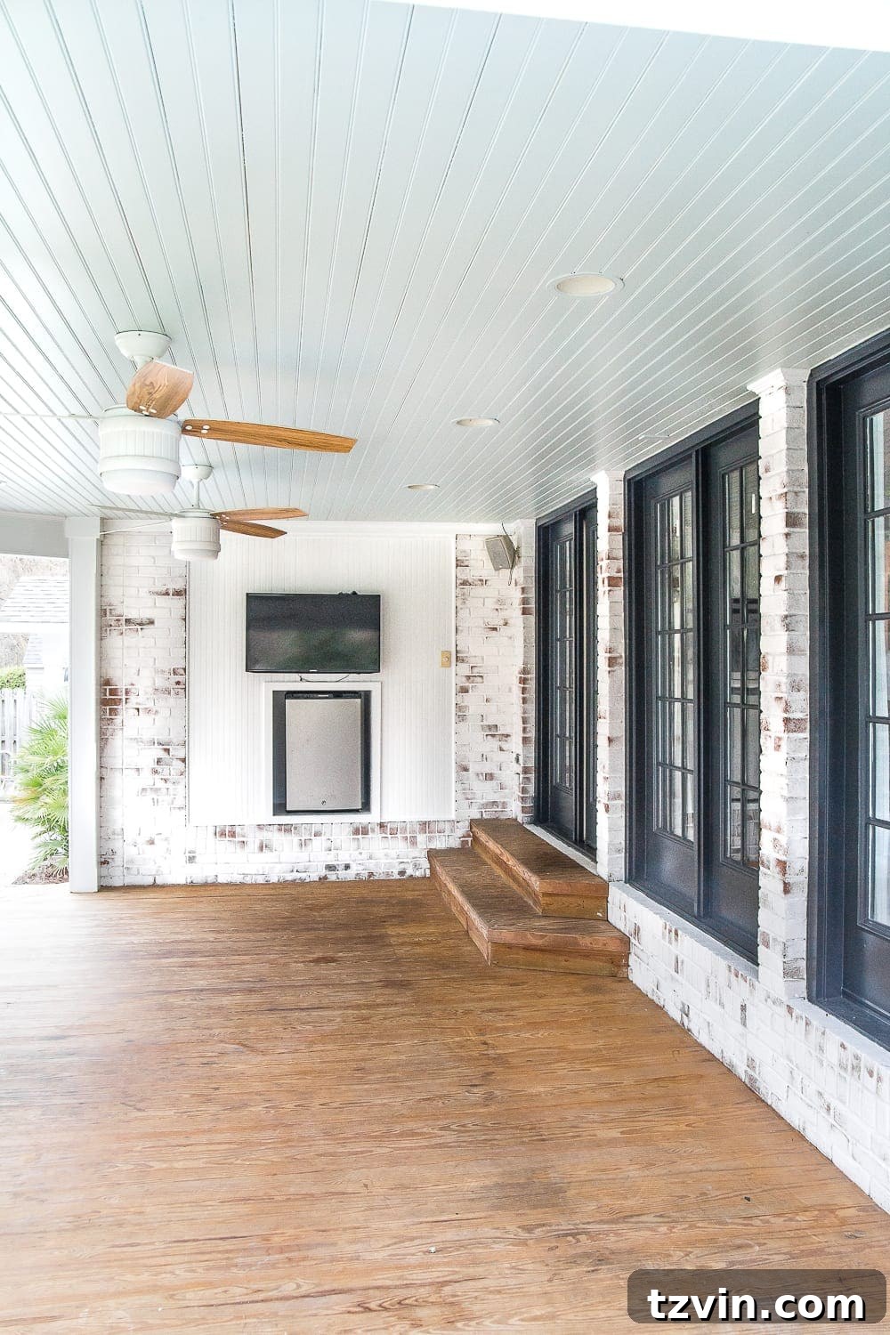 DIY Fireplace Creations for Any Space 3 Before shot of the back porch wall, featuring a television and mini-refrigerator setup.