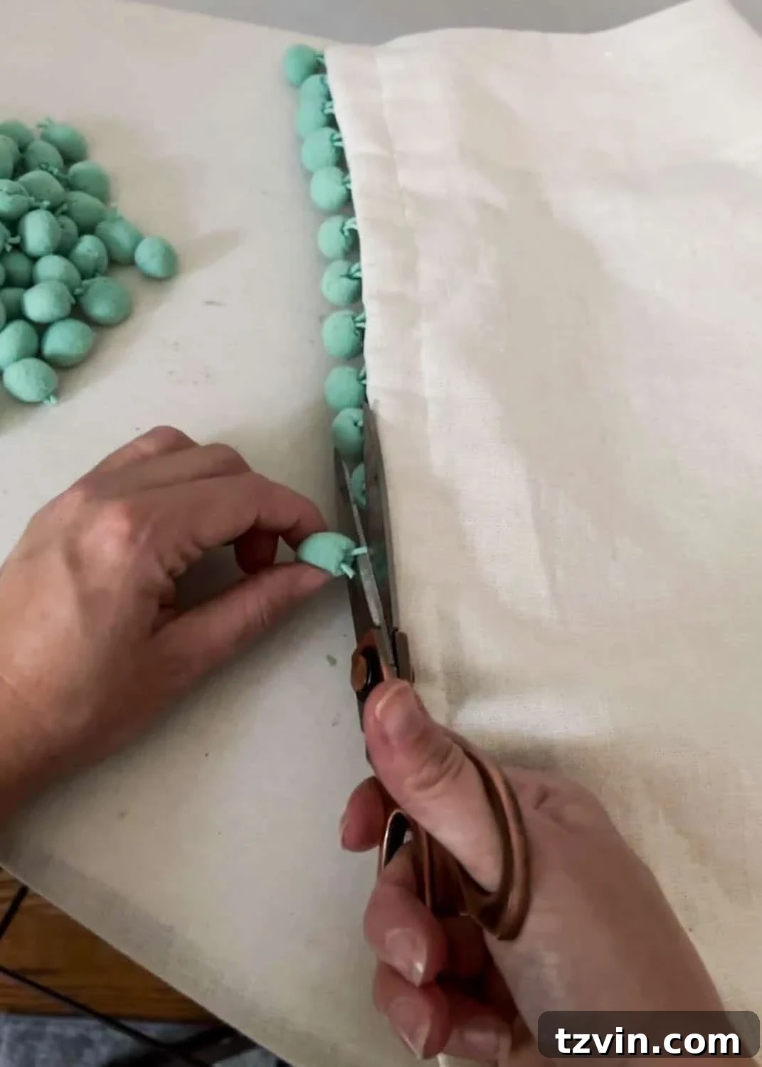 Chic No-Sew Curtains: Easy DIY with Designer Trim 5 Carefully removing pom-poms from old curtains with fabric scissors for upcycling