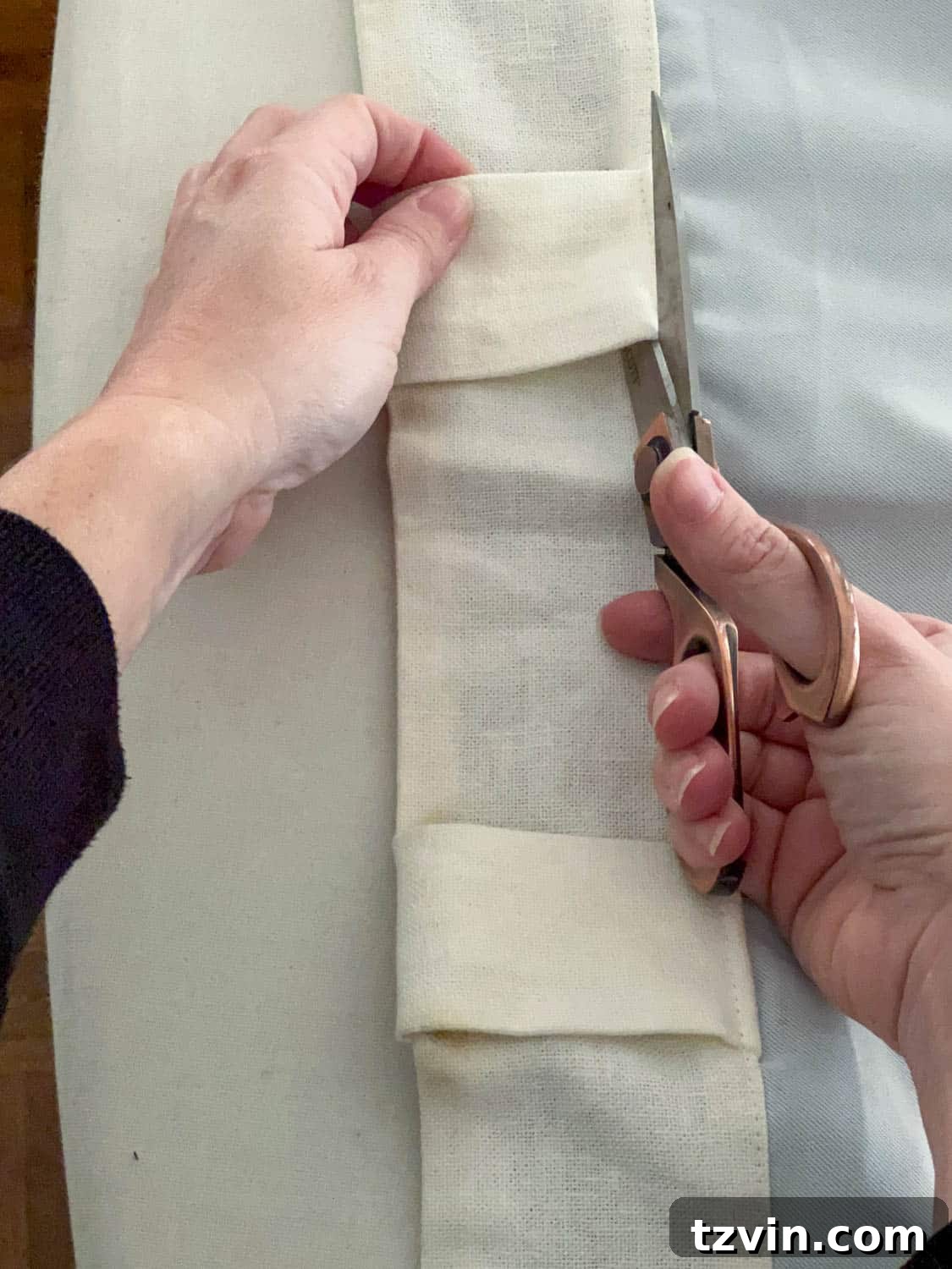 Chic No-Sew Curtains: Easy DIY with Designer Trim 6 Cutting off back tabs of a curtain panel with scissors to prepare for a new header