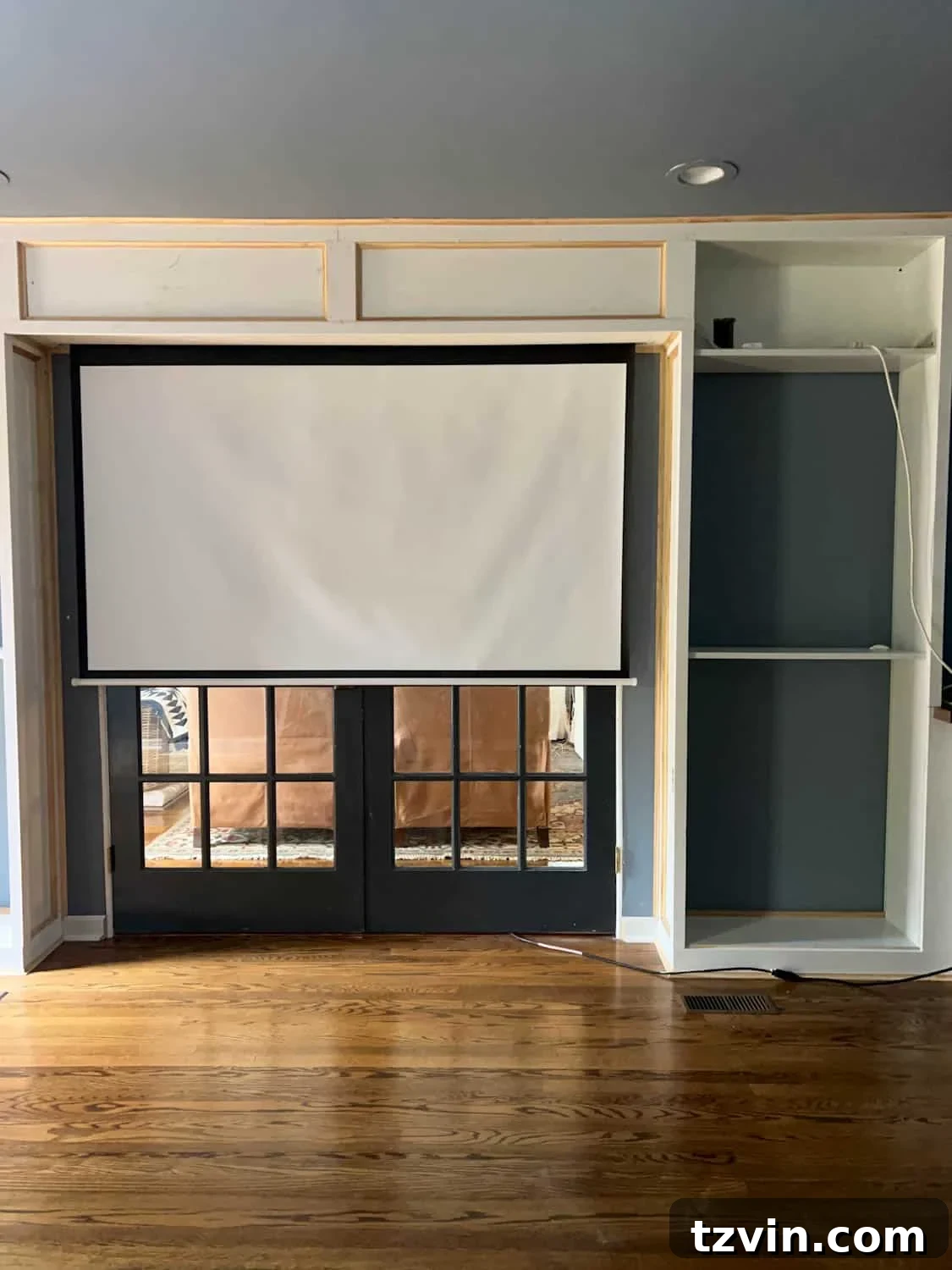 Akıllı IKEA Hack: Gizli Projeksiyon Perdesi Nasıl Yapılır 15 The fully integrated hidden projector screen, nestled between built-in bookcases above French doors, awaiting final decorative touches
