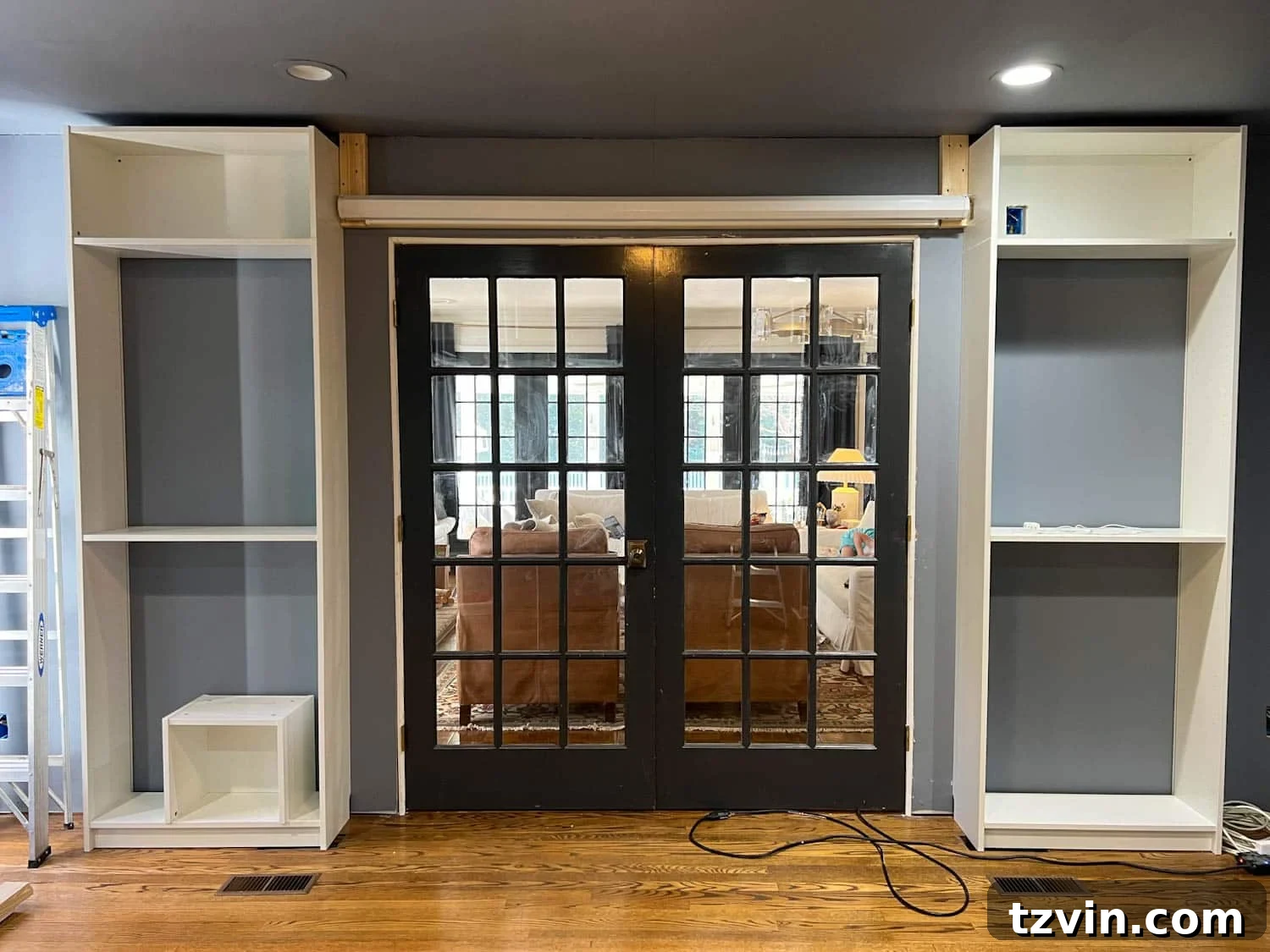 Akıllı IKEA Hack: Gizli Projeksiyon Perdesi Nasıl Yapılır 5 Projector screen support system being installed with 2x4s above French doors before the box enclosure