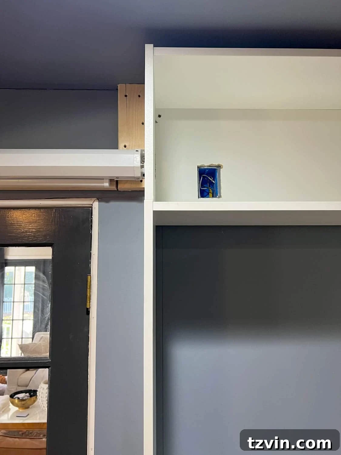 Akıllı IKEA Hack: Gizli Projeksiyon Perdesi Nasıl Yapılır 8 Close-up of cutting a hole for an electrical outlet in a bookcase using a jigsaw for precision