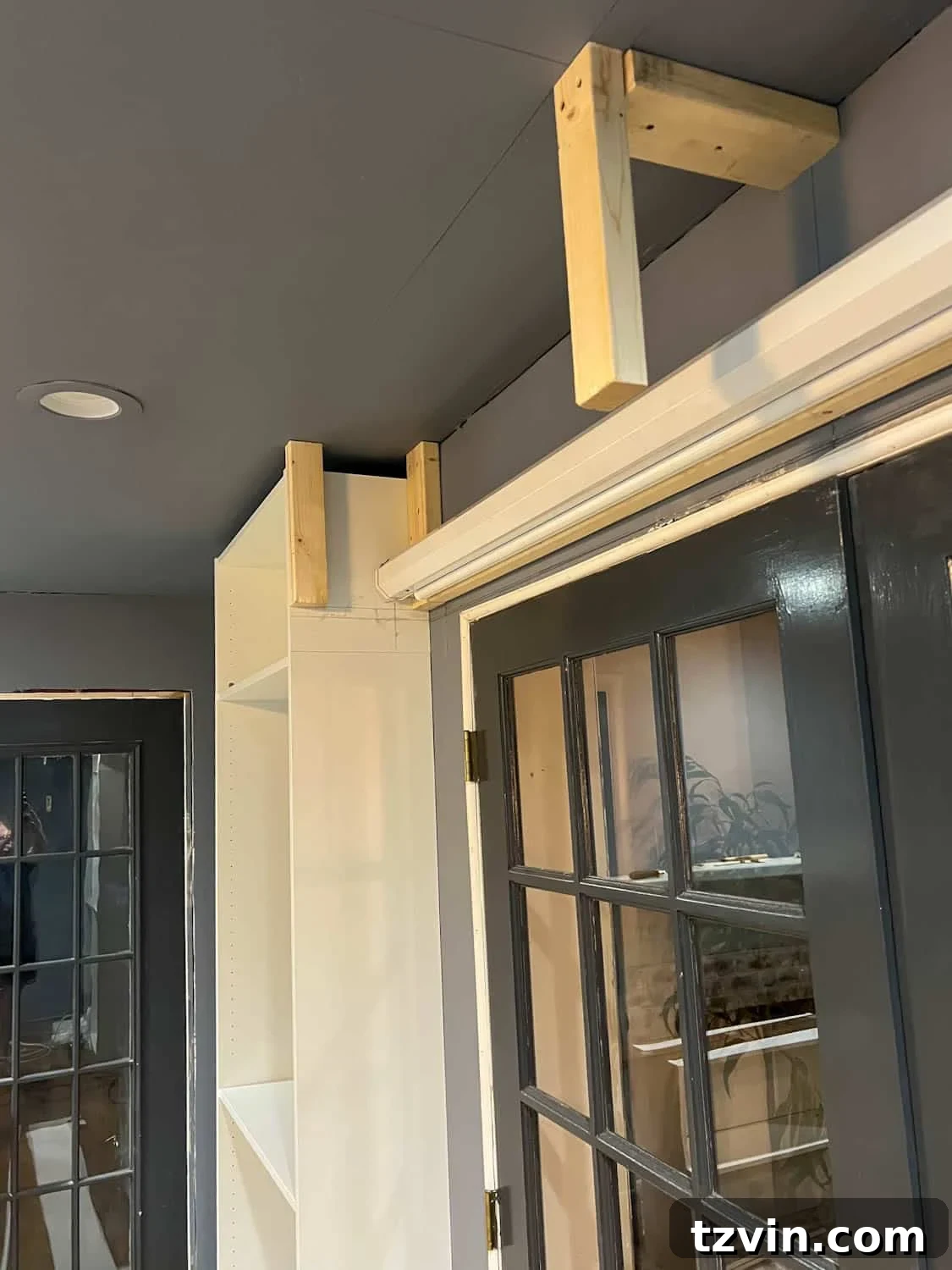 Akıllı IKEA Hack: Gizli Projeksiyon Perdesi Nasıl Yapılır 9 Anchoring 2x4 braces securely between bookcases to form the top structure of the hidden screen box