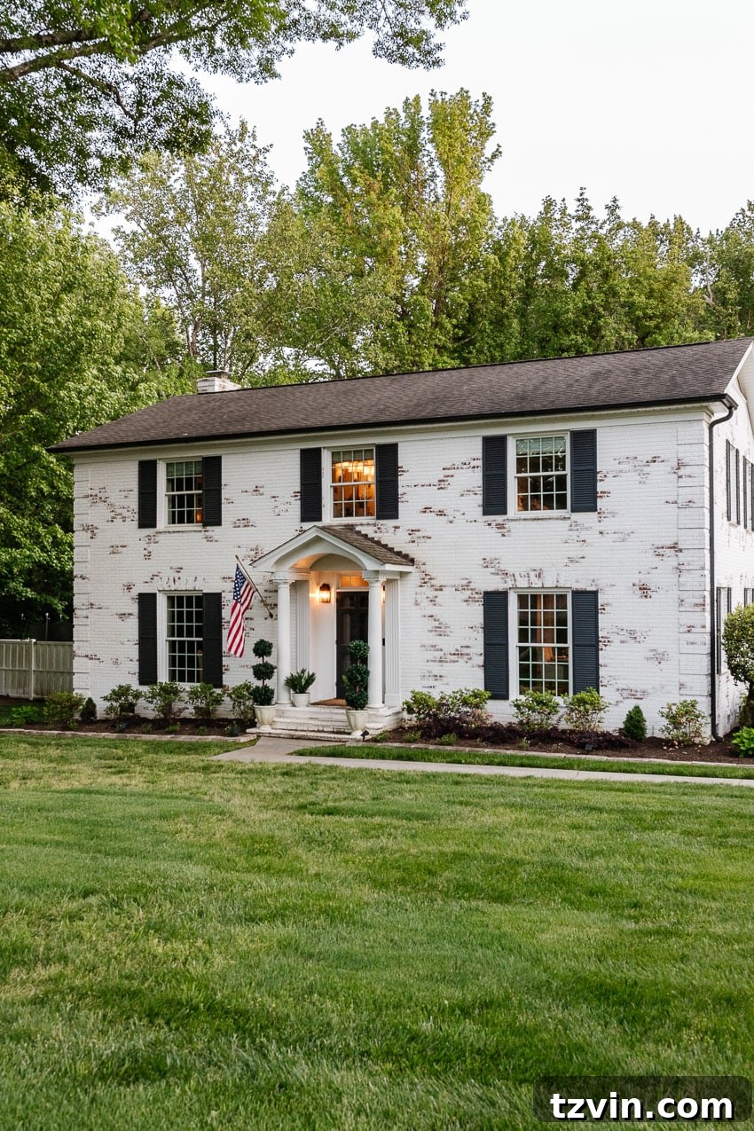 From Patchy to Pristine: Our Year-Long Lawn Makeover 13 A charming white brick house with a newly transformed, vibrant green lawn in front, showcasing improved curb appeal.