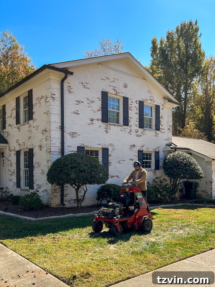 From Patchy to Pristine: Our Year-Long Lawn Makeover 8 A person riding an aerator across a lawn in the fall, preparing the soil for planting new grass seed, highlighting the aeration process.