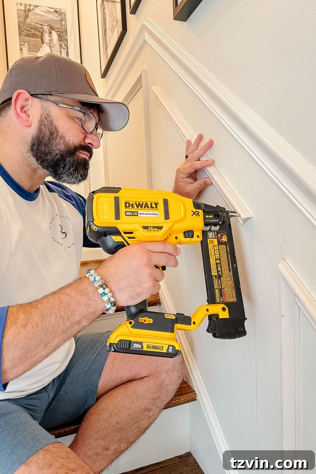 Stair Wainscoting Made Simple: A DIY Installation 14 Nailing angled molding on stairs to create custom wainscoting panels