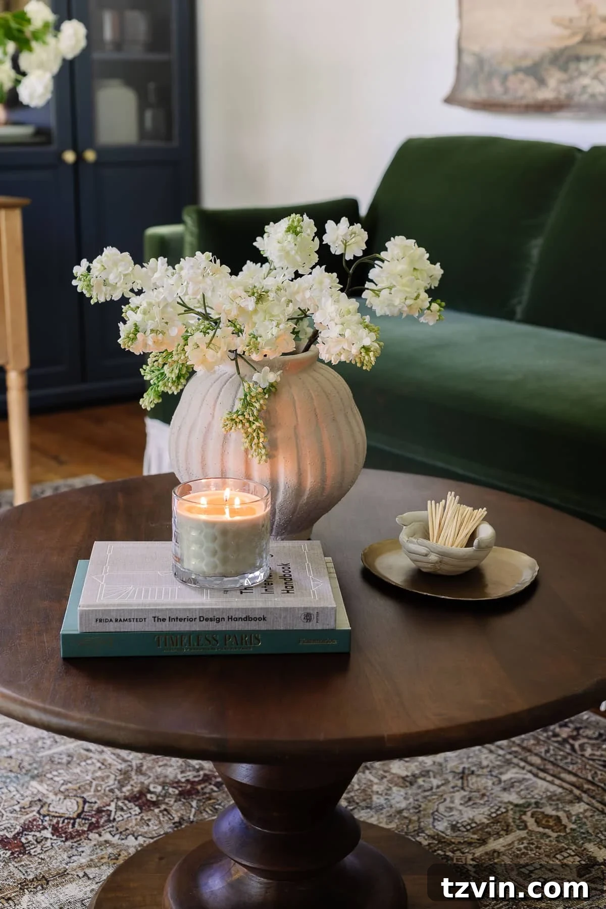 Boost Your Output: Smart Home Office Designs 11 Charming coffee table decor featuring a vase of fresh flowers, inspiring coffee table books, a lit candle, a decorative tray, and a stoneware bowl for matches