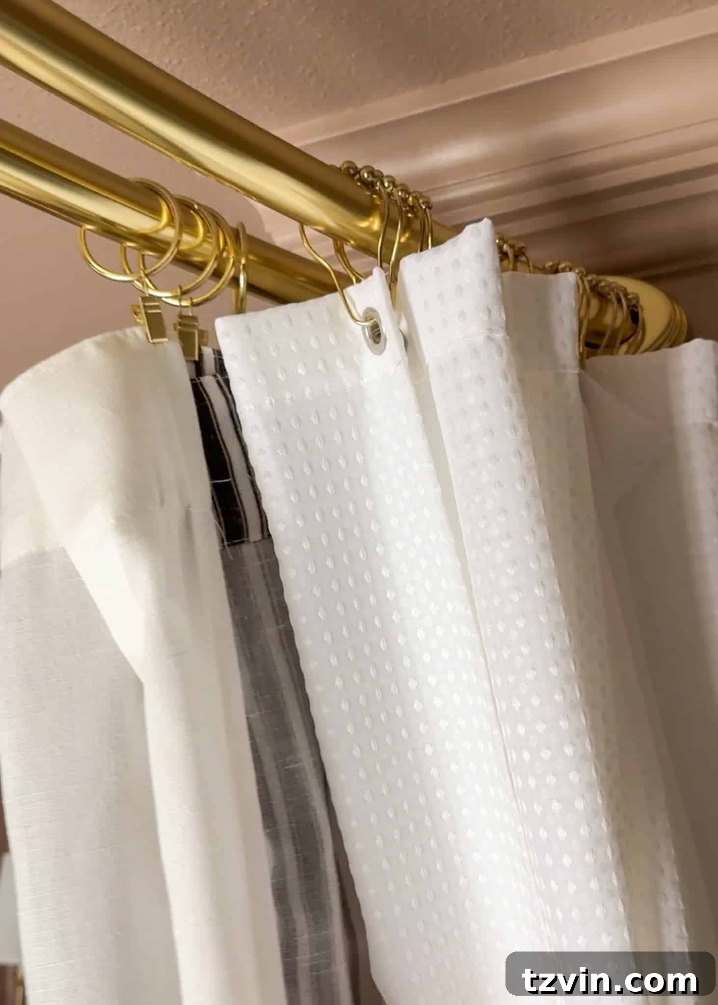 A person carefully hanging an extra-long waterproof shower curtain liner onto the inner rod of a double shower curtain system, demonstrating the correct method for the first layer of a high-hung curtain.