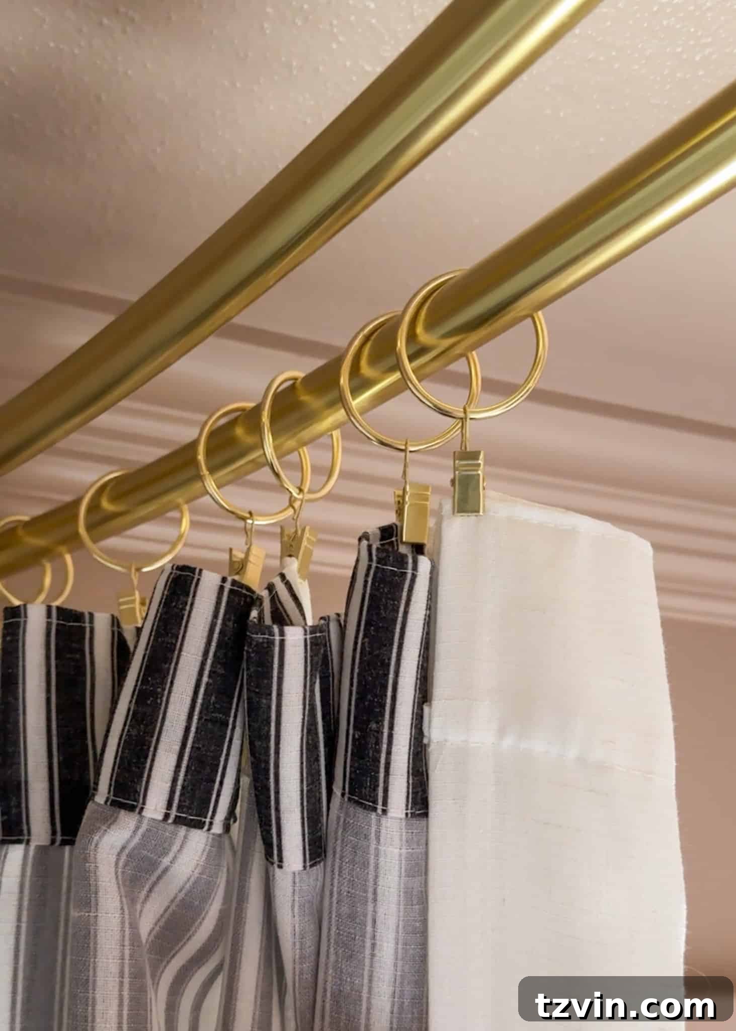 A close-up view of a decorative window curtain panel being attached to the outer rod of a double shower curtain system using curtain ring clips, highlighting the elegant draping and custom fit.