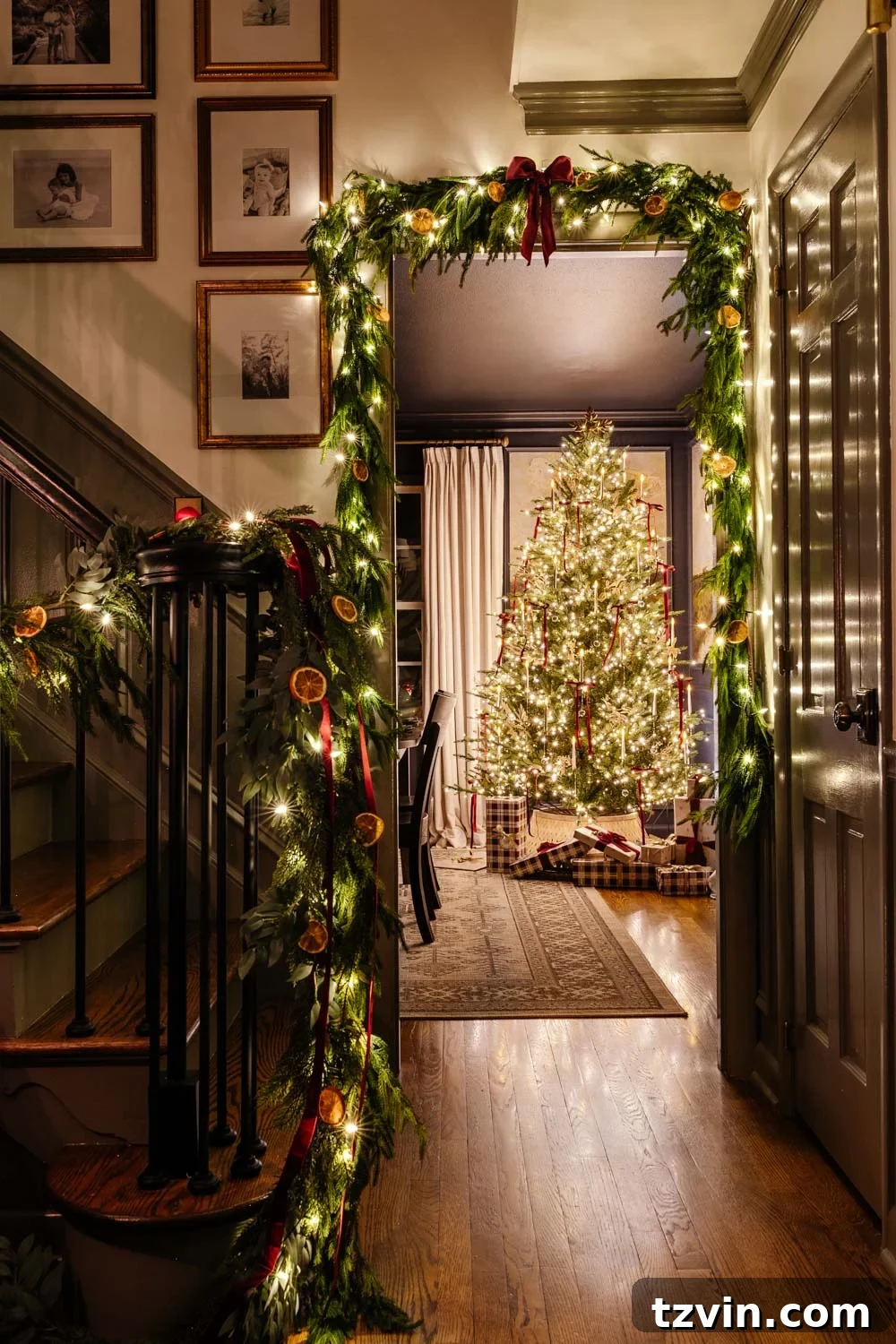 Christmas candlelight home tour view from doorway, showcasing elegant garland and a sparkling tree in the background.