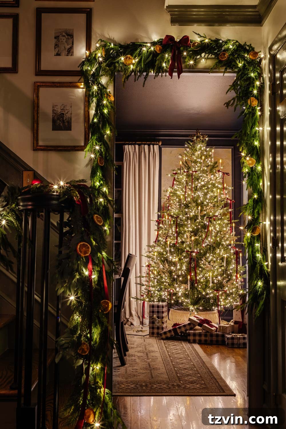 Cozy candlelight Christmas home tour through a doorway, adorned with festive garland and a glimpse of the illuminated Christmas tree.