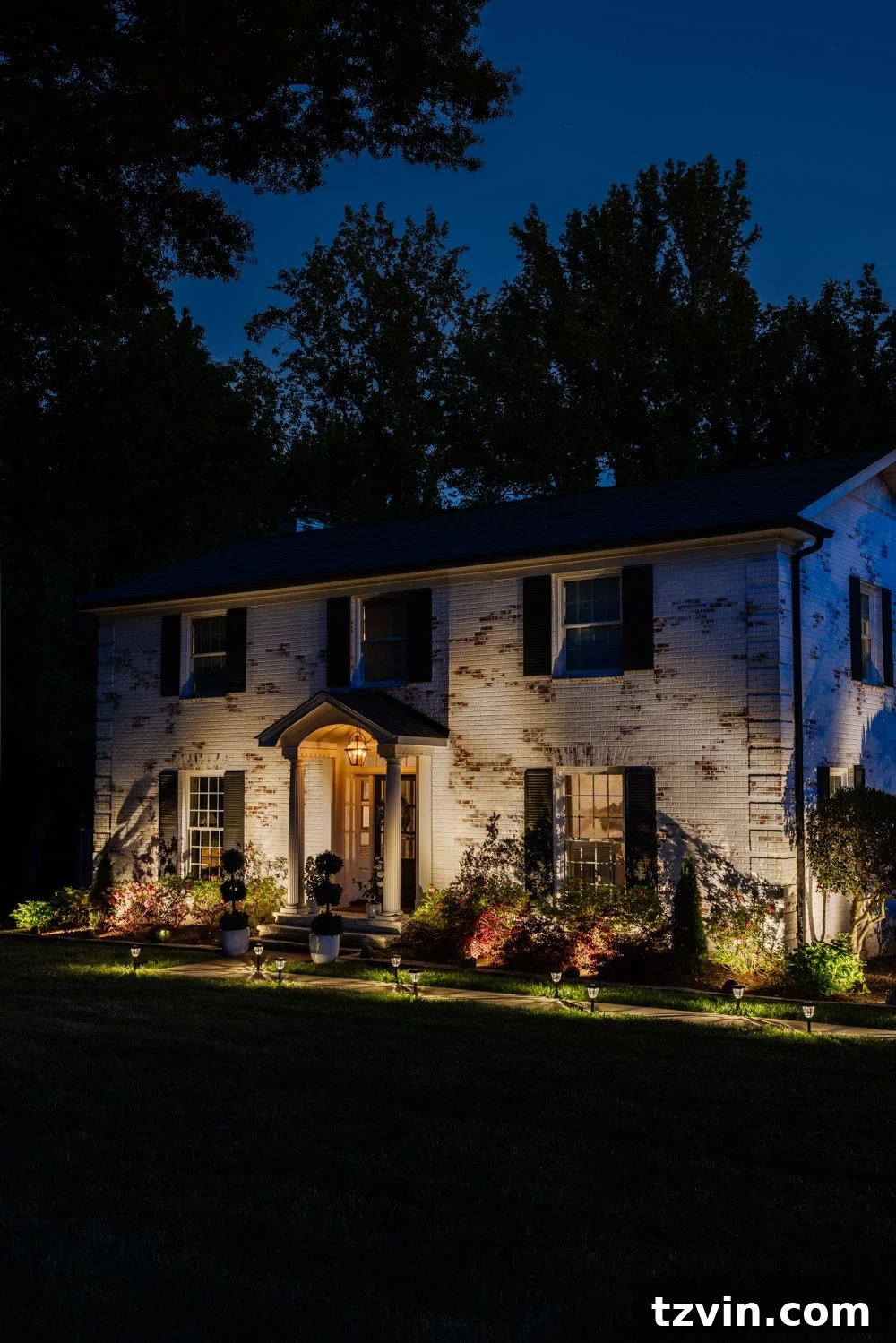 Wow-Worthy DIY Front Yard Transformations 2 Illuminated front yard and limewashed colonial house at night showcasing enhanced curb appeal with solar spot lights