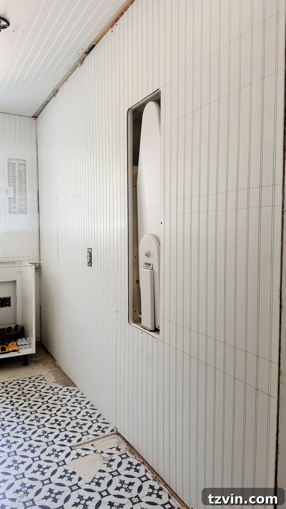 Built-in ironing board storage discreetly tucked between wall studs in a laundry room.