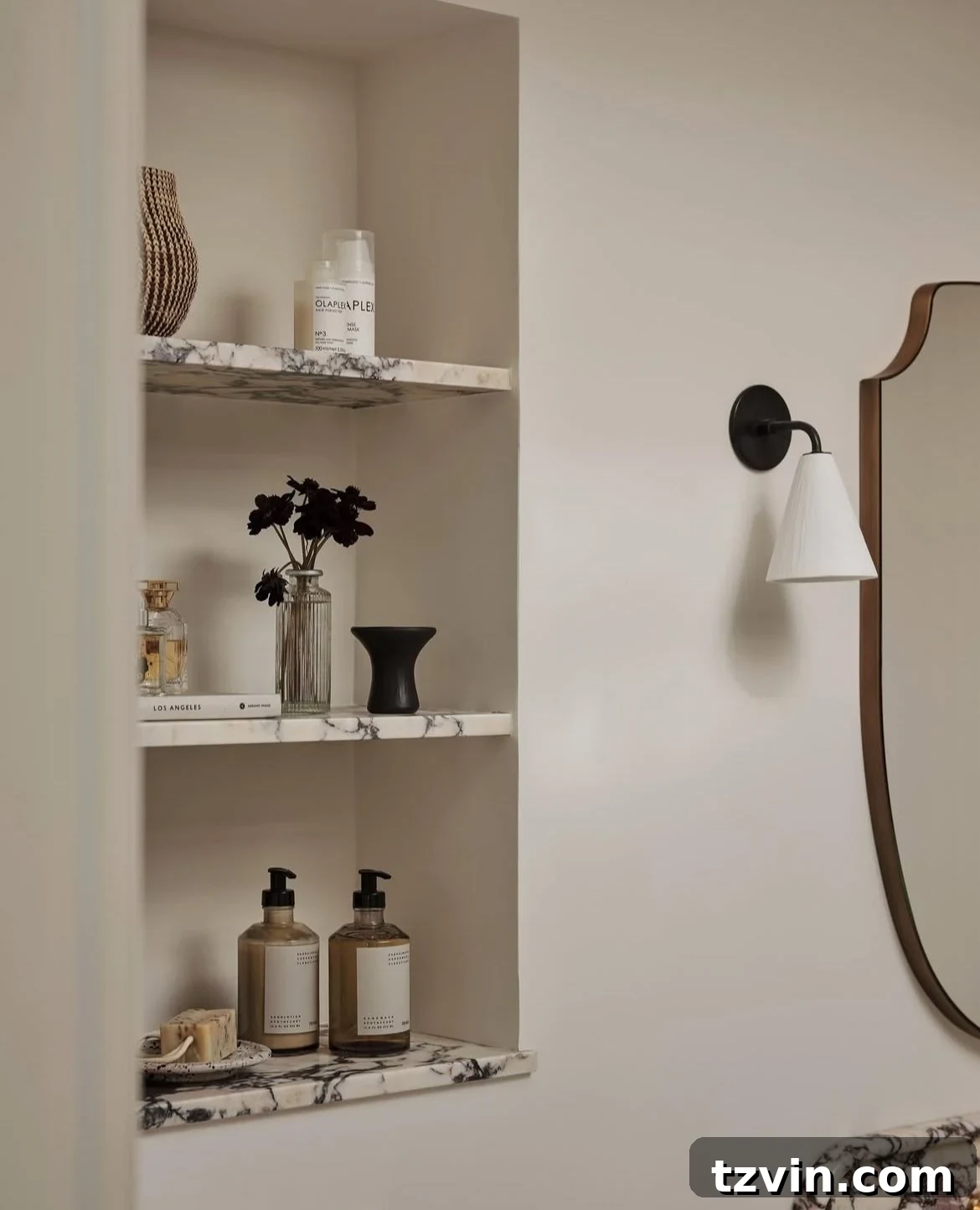 Recessed bathroom shelves between studs, holding toiletries and decorative items.