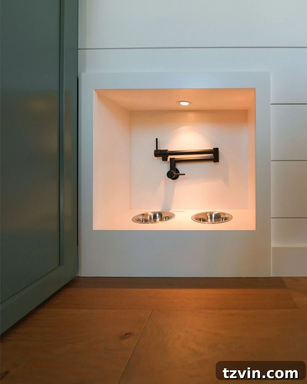 Recessed pet feeding station with built-in food and water bowls at baseboard height.