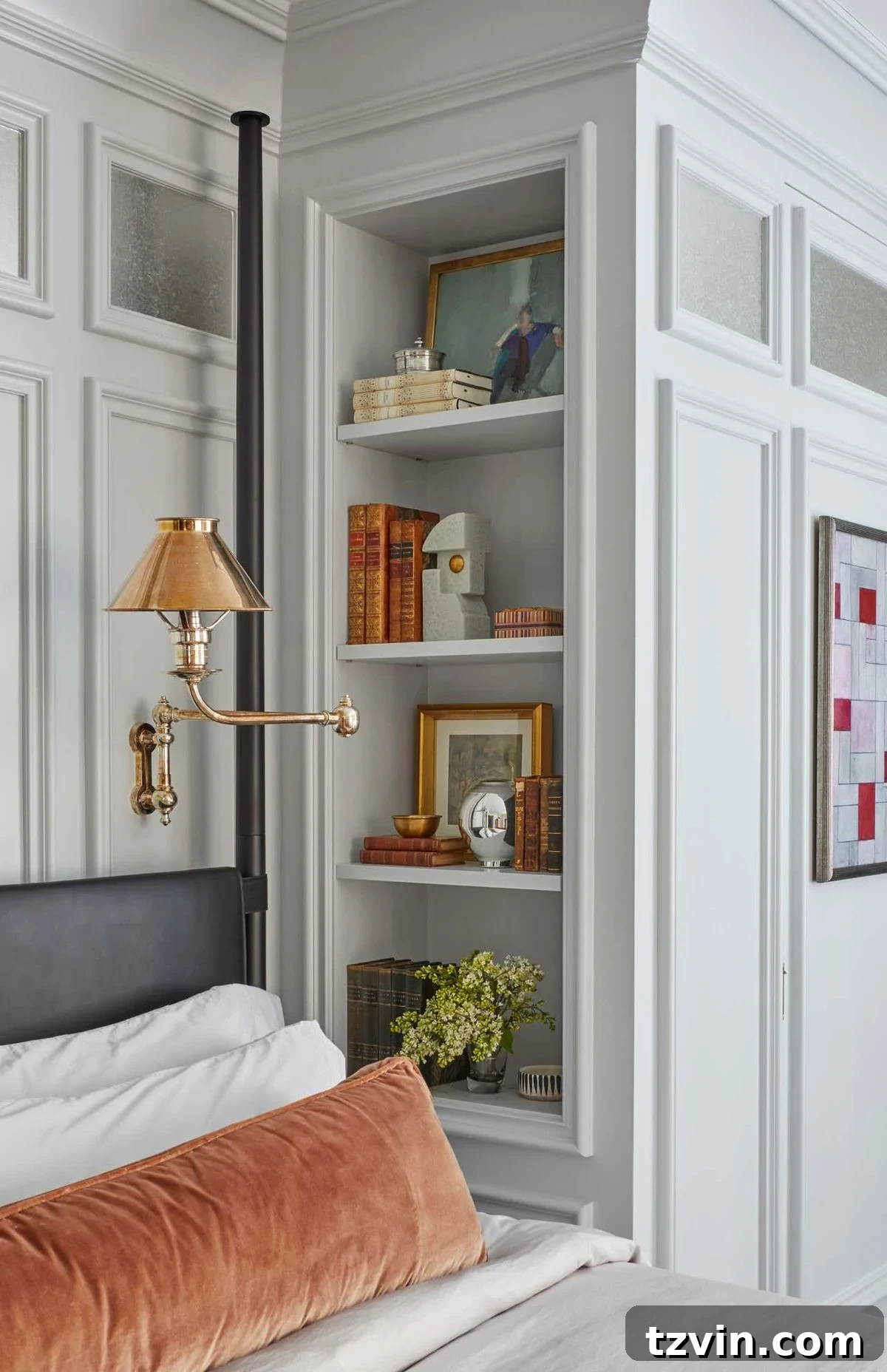Recessed shelves beside a bed functioning as a minimalist nightstand, built into the wall.