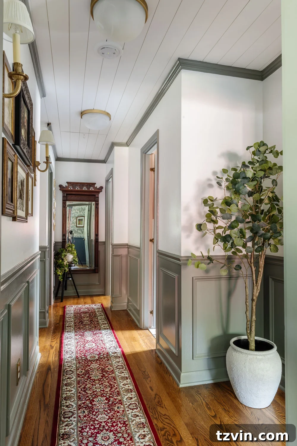 A cohesive hallway design with consistent flooring, decor, and art leading to another room.