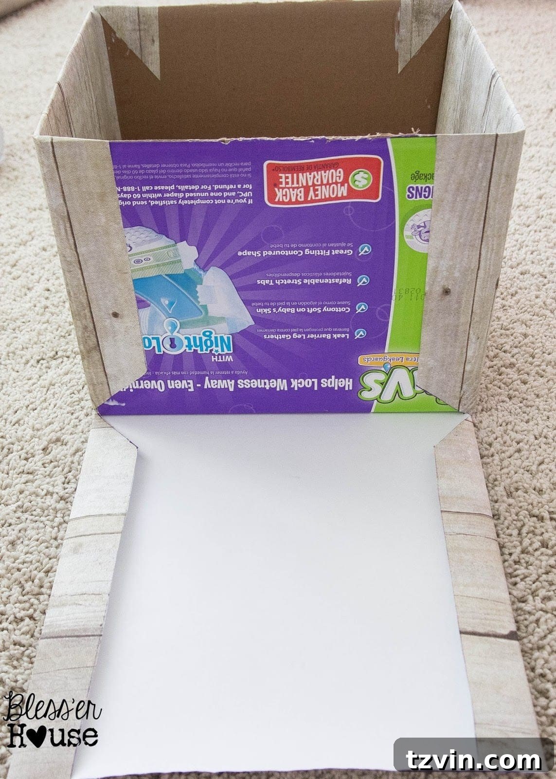 Faux wood paper being folded and prepared to wrap the remaining sides of the cardboard box for a clean finish.