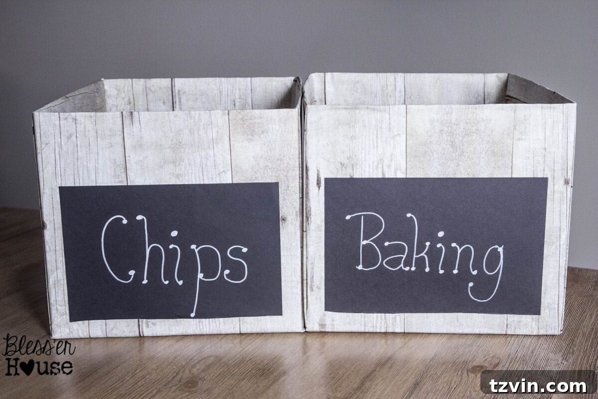 A close-up of a DIY weathered wood pantry crate with a custom black cardstock chalkboard label, showcasing its removable feature.