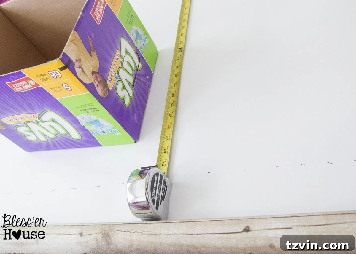 Faux wood craft paper being measured and cut to size for wrapping a cardboard diaper box.