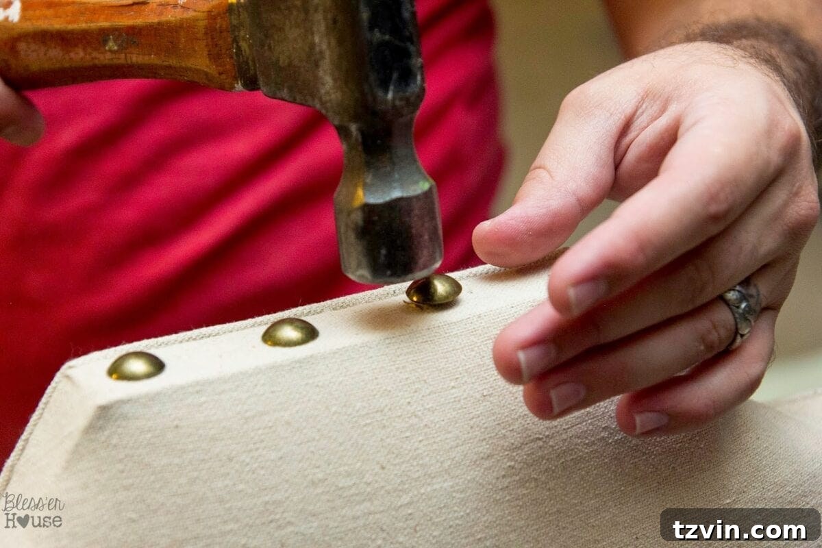 Hammering in antique gold nailheads on the dining chair