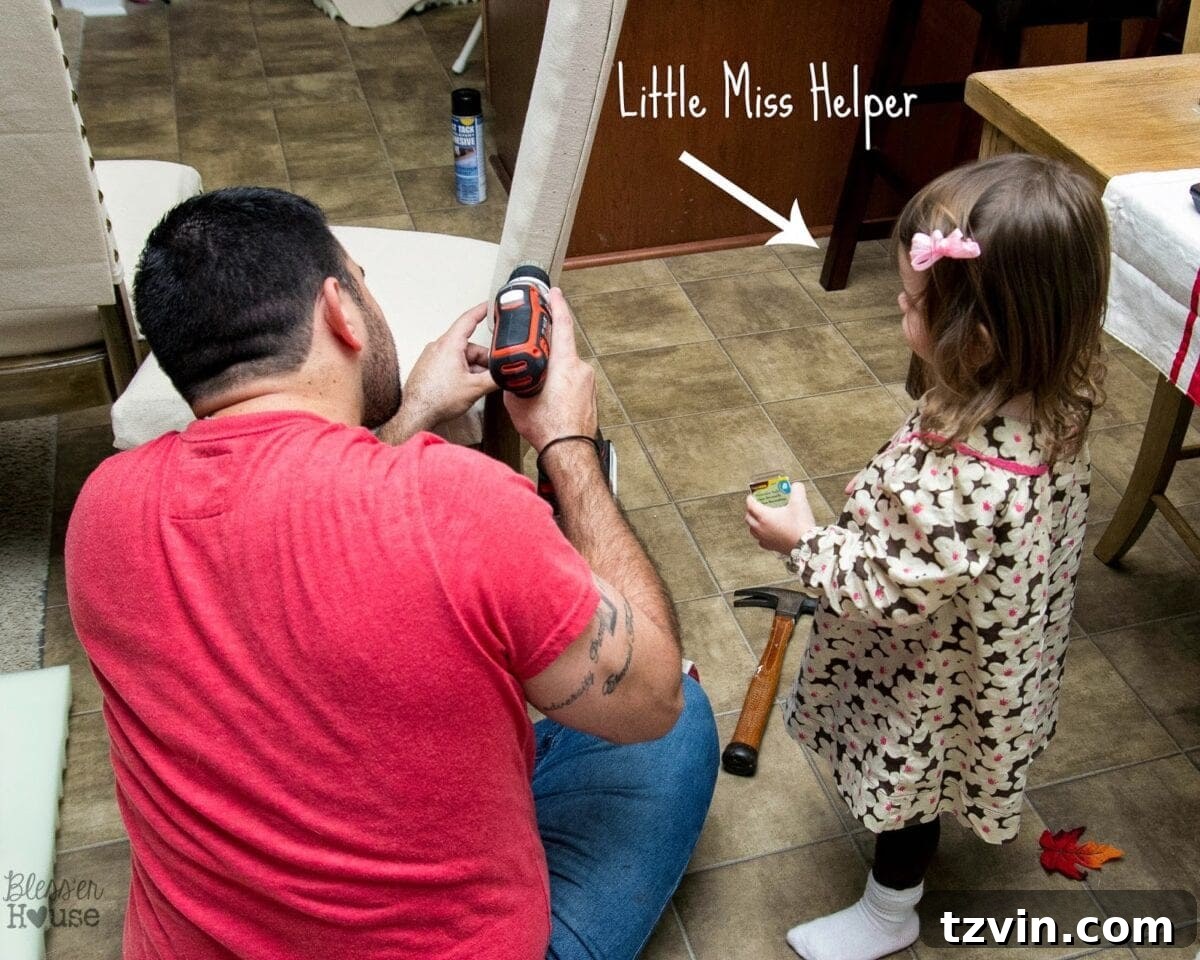 Child helping by handing nailheads during chair upholstery