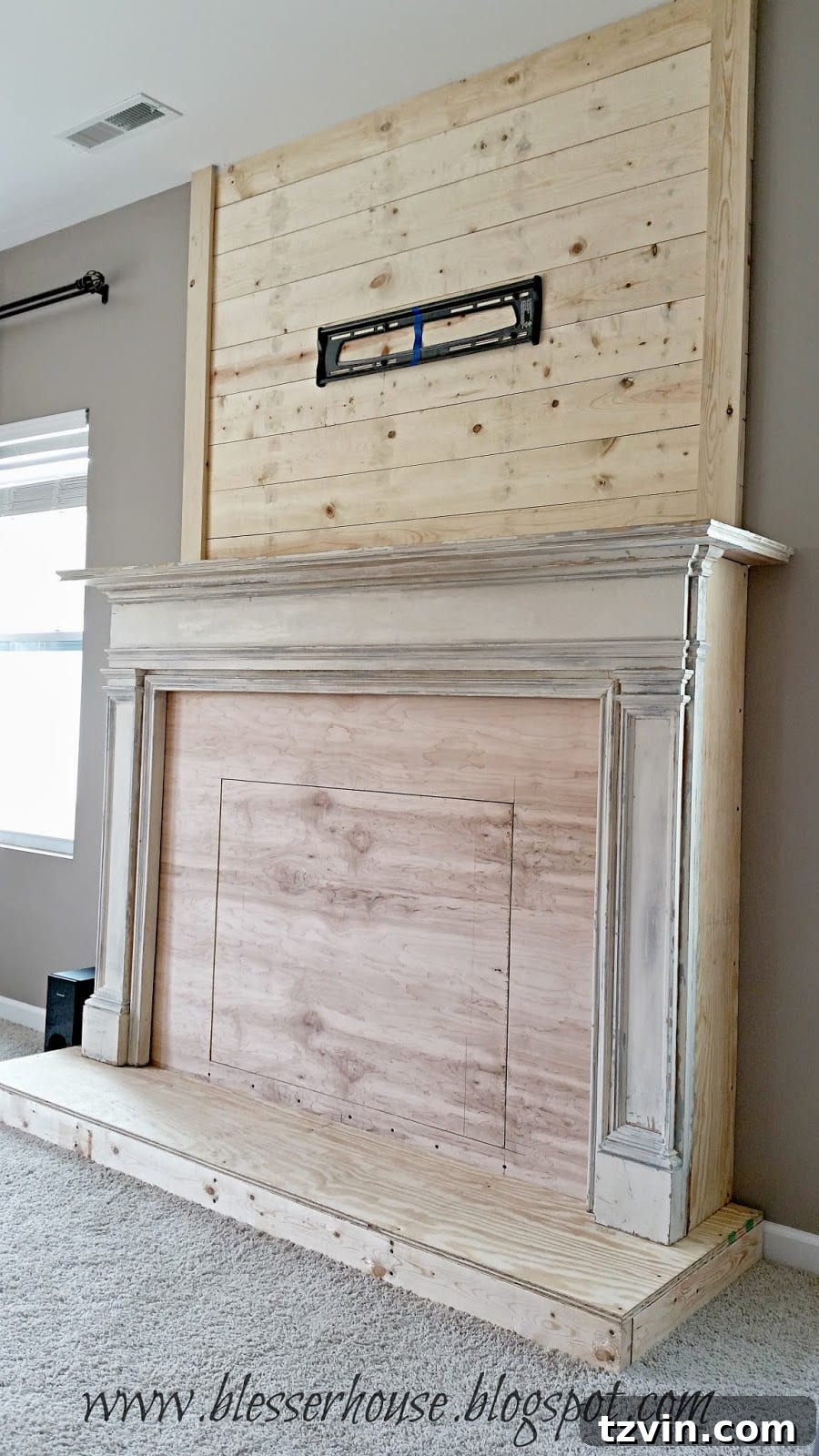 The newly installed plank wall above the faux fireplace, now fully constructed and ready for painting and final decorative touches.