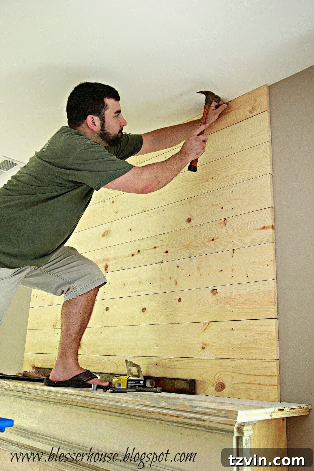 Cutting the last plank to fit snugly against the ceiling for the DIY plank wall, ensuring a precise and finished edge.